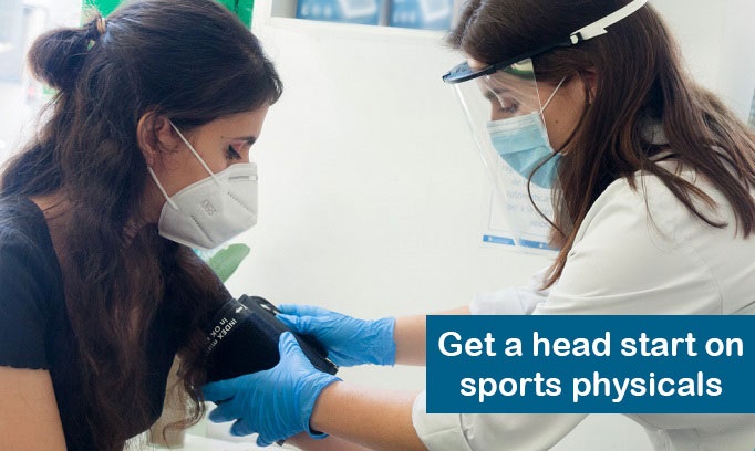 teen girl with long dark hair wearing face mask has BP taken as part of a sport physical by female doctor
